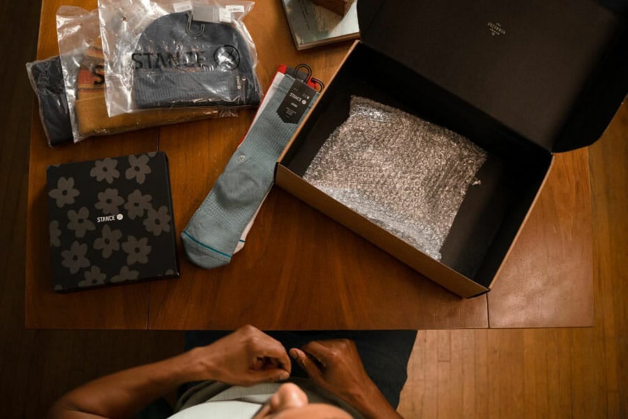 Customer sitting at a table with Stance apparel taken out of the box.