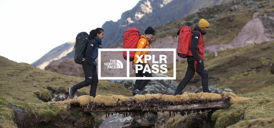 Three people hiking in the mountains with a North Face logo and ‘XPLR PASS’.