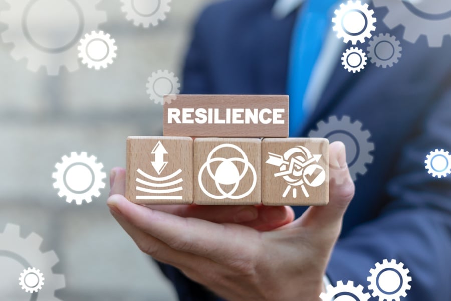 Person holding wooden blocks the have images and the word resilience.