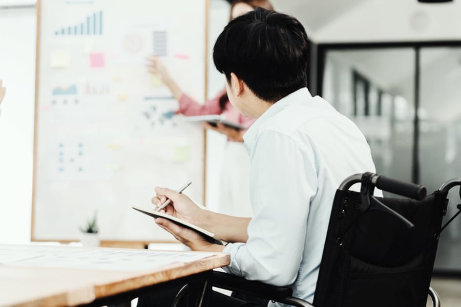 Ryder employee using a wheelchair working at a whiteboard in an office