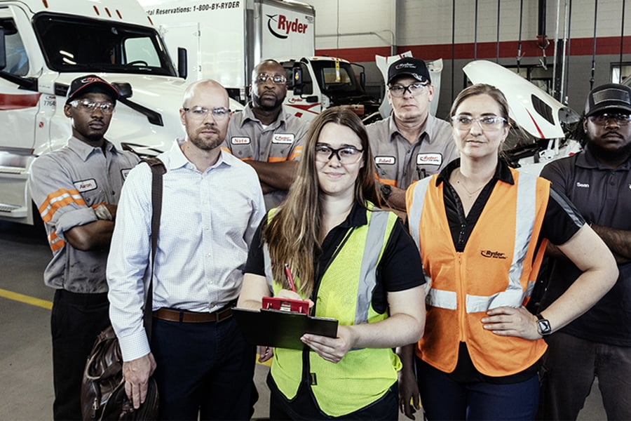 A group of Ryder technicians and staff gathered together in a maintenance shop