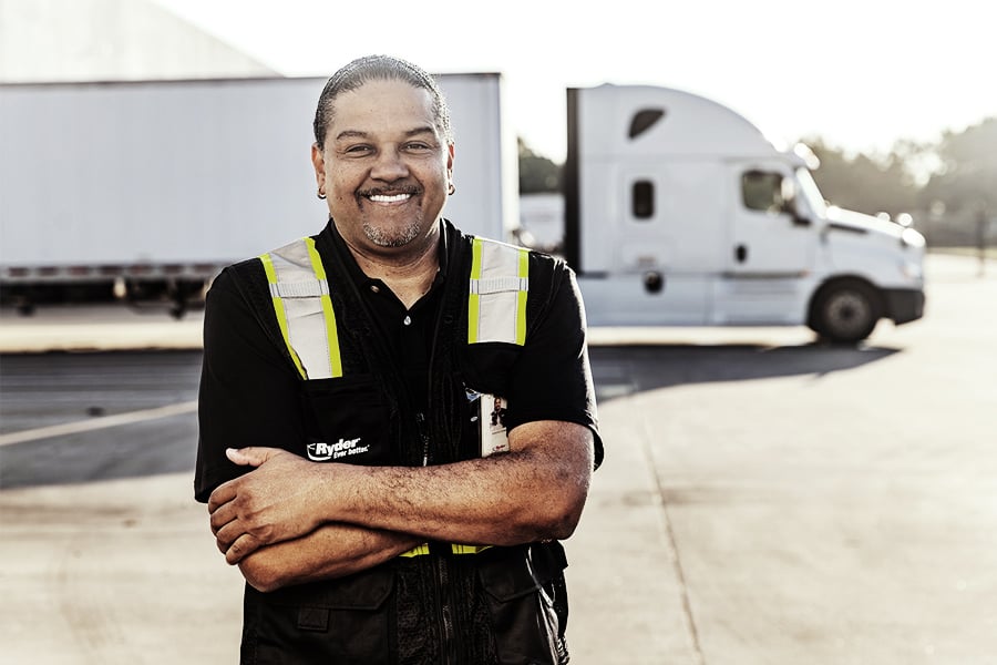 Ryder CDL truck driver standing with arms crossed in front of a semi truck