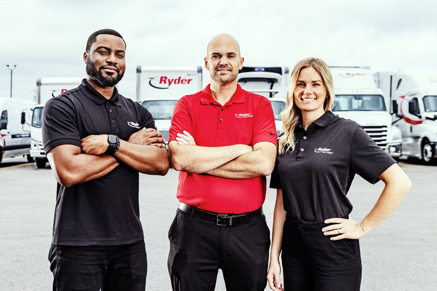 Three Ryder employees standing in front of a Ryder truck fleet