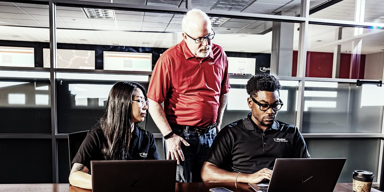 Three Ryder logistics professionals reviewing carrier data together
