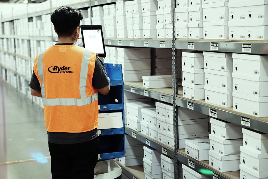 Ryder warehouse worker picking retail orders from shelving with a mobile cart Ryder warehouse worker picking retail orders from shelving with a mobile cart