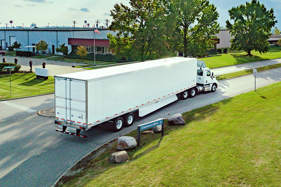 White Ryder semi truck with a dry van trailer turning onto a commercial park road White Ryder semi truck with a dry van trailer turning onto a commercial park road