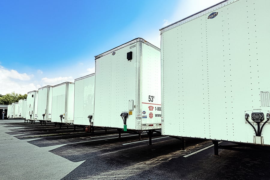 Row of white commercial dry van trailers parked in a Ryder trailer rental lot Row of white commercial dry van trailers parked in a Ryder trailer rental lot