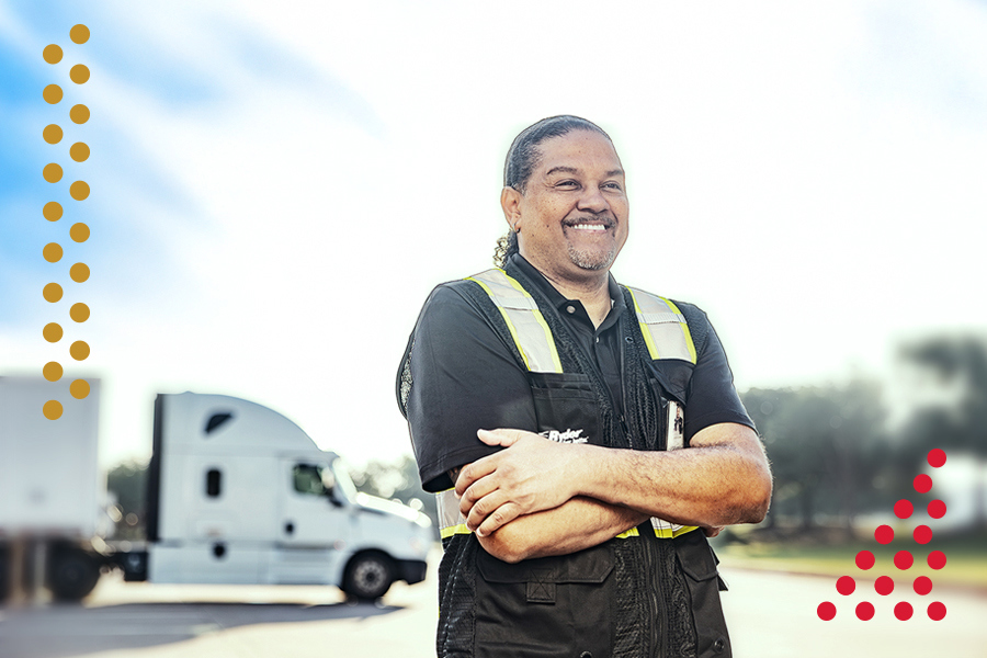 Truck driver standing with arms crossed in front of a semi-truck
