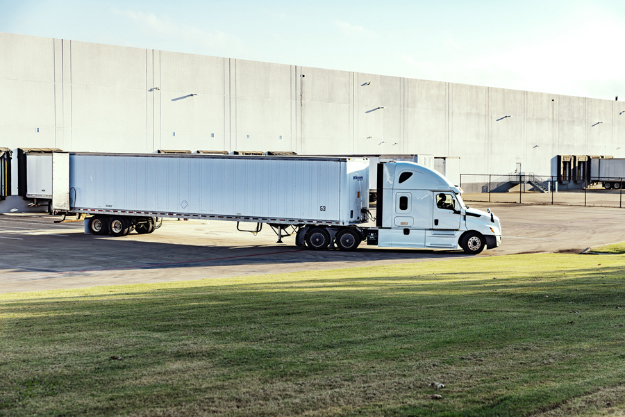 Semi-truck with trailer parked at a warehouse loading dock