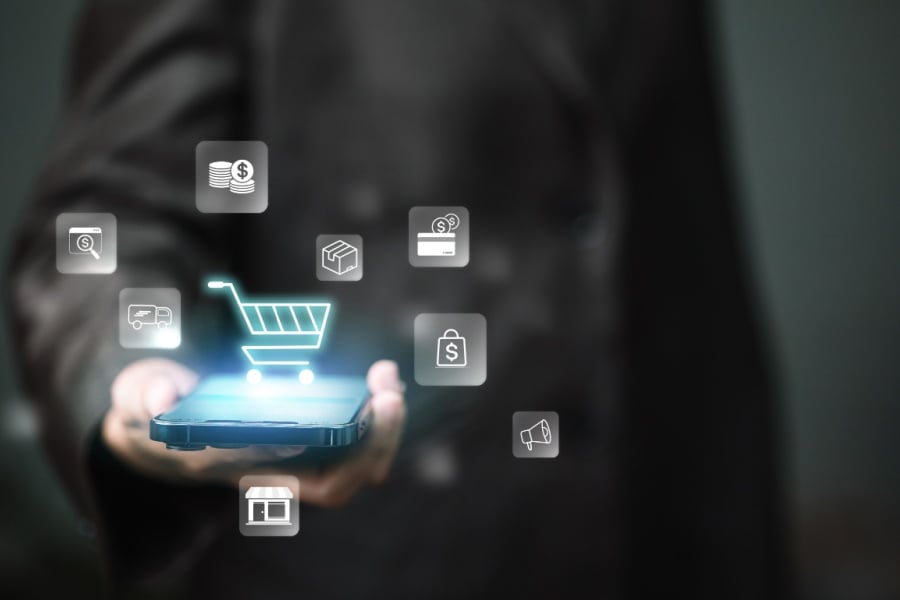 Why Omnichannel Fulfillment is Important in 2026 Person presents smartphone with glowing shopping cart and retail icons, representing mobile e-commerce, online payments, checkout, marketing automation and omnichannel sales growth