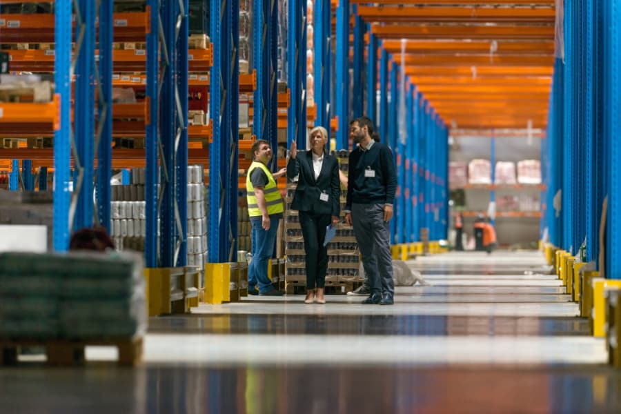 Finding the Right Option for Your Supply Chain Two businesspeople discuss third-party and fourth-party logistics services with a worker inside a warehouse