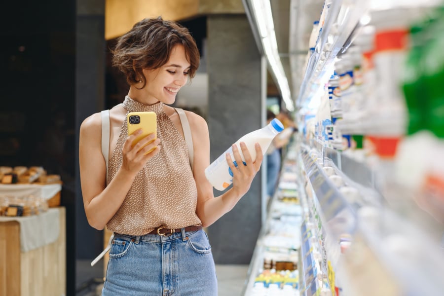Woman using mobile phone while grocery shopping